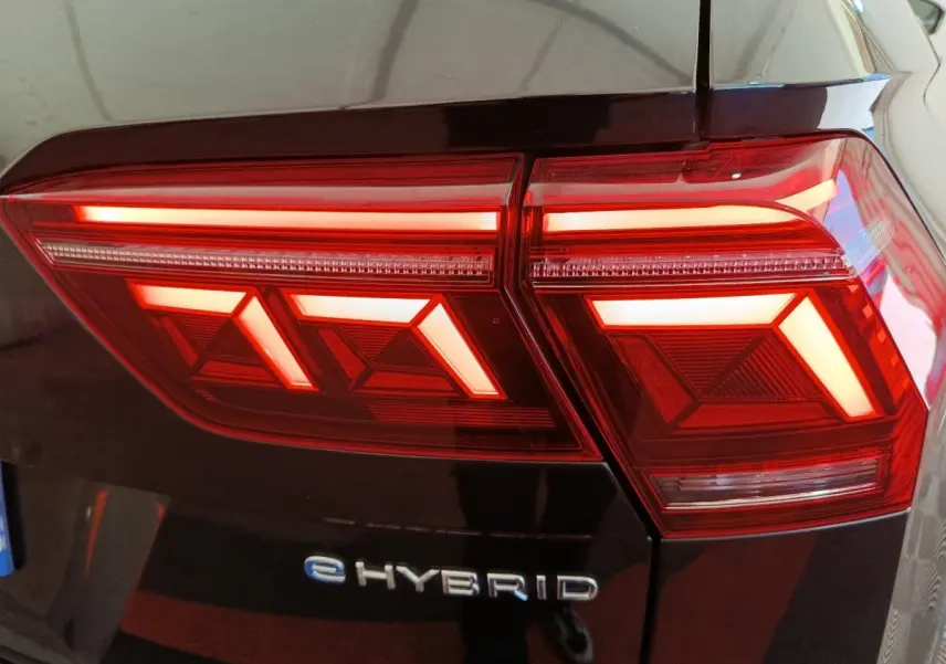 Gros plan sur le feu arrière droit rouge et blanc d’un Volkswagen Tiguan noir eHYBRID 2023.