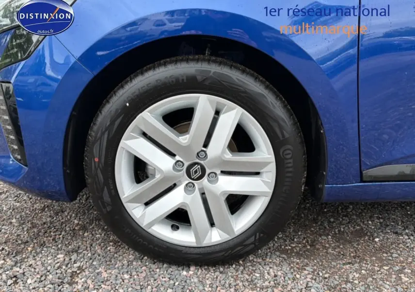 Gros plan sur la roue avant gauche d'une Renault Clio V bleu iron avec jante alliage et logo Renault central.
