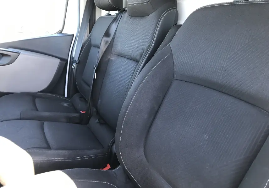 Vue rapprochée des sièges avant noirs du Renault Trafic Fourgon blanc, version l1 h1 2017, montrant les ceintures de sécurité.
