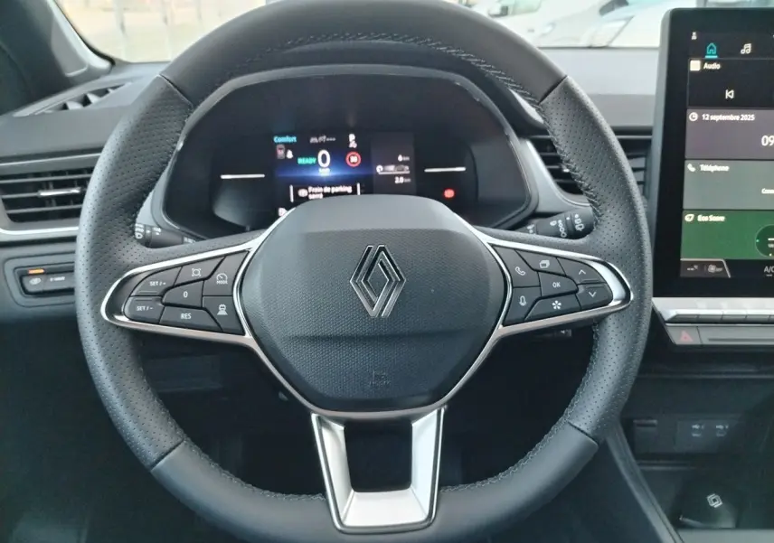 Volant en cuir noir perforé avec logo Renault au centre, tableau de bord numérique et écran tactile à droite.