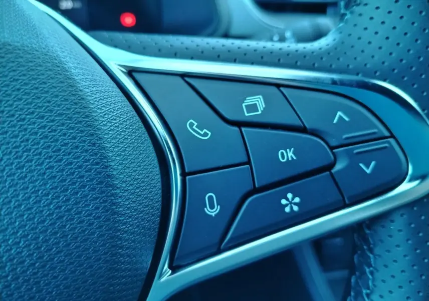 Gros plan sur les boutons de commande au volant côté gauche du Renault Captur gris cassiopée toit noir 2025.