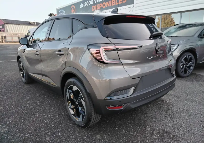 Vue 3/4 arrière gauche d'un Renault Captur gris Cassiopée avec toit noir et jantes noires brillantes.