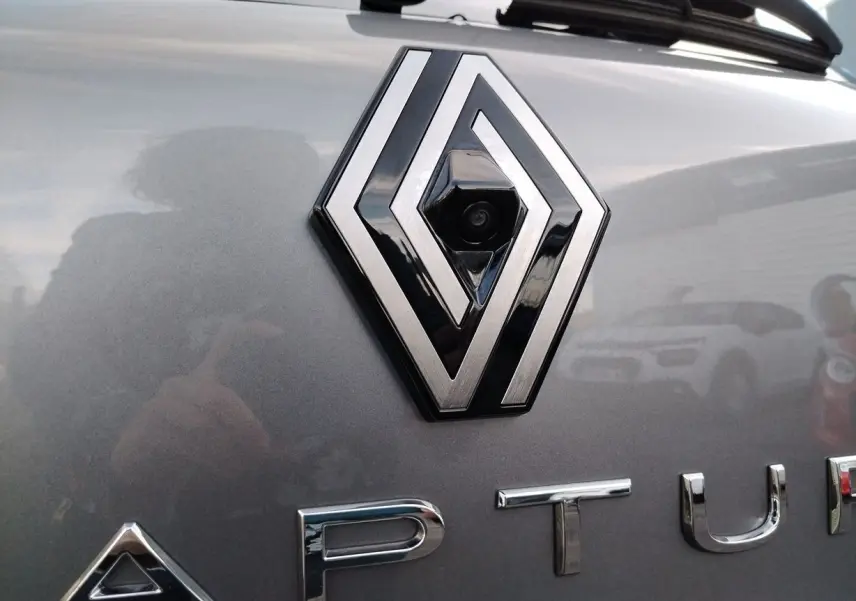 Gros plan sur le logo Renault avec caméra intégrée sur la malle arrière d'un Captur gris Cassiopée 2025.