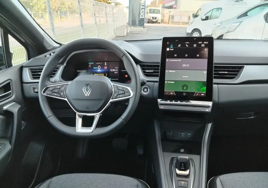 Vue intérieure du tableau de bord du Renault Captur E-Tech 2025, avec volant multifonction et écran tactile central.