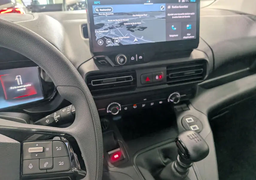 Intérieur du Citroën Berlingo 2025 blanc, vue du tableau de bord avec écran tactile et levier de vitesse manuel.