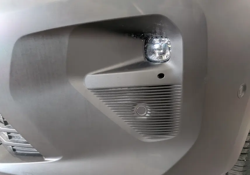 Gros plan sur le pare-chocs avant droit blanc du Citroën Berlingo 2025, avec antibrouillard et capteur de stationnement.