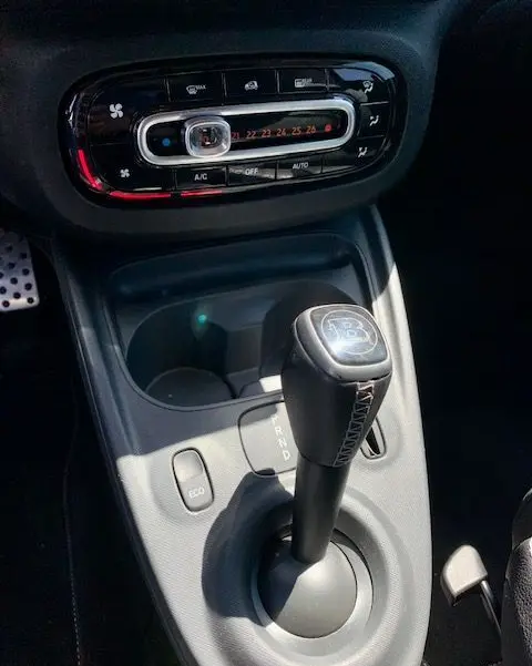 Gros plan sur la console centrale d'une Smart Fortwo électrique grise 2019, mettant en valeur le levier de boîte automatique Brabus.
