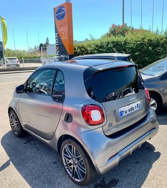 Vue 3/4 arrière droite d'une Smart Fortwo Coupé électrique Brabus Style 2019 gris métallisé stationnée en extérieur.