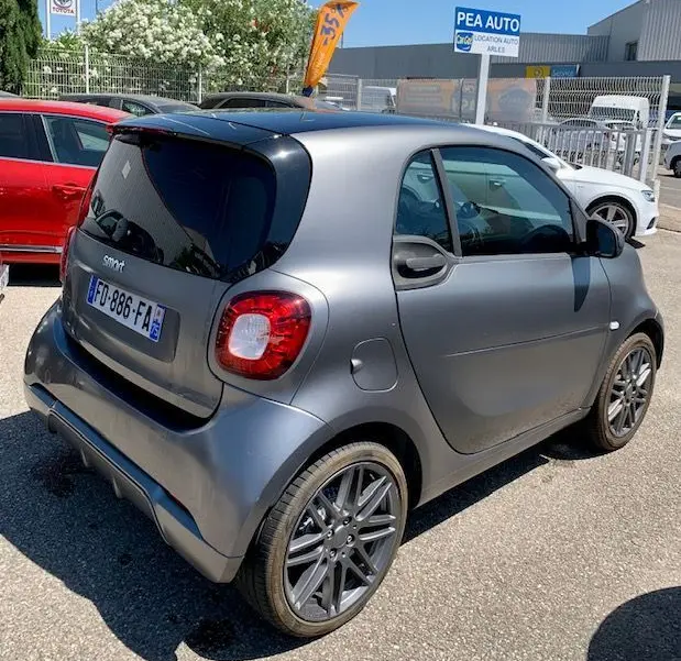 Vue 3/4 arrière droite d'une Smart Fortwo électrique Brabus style gris métallisé avec jantes sport et toit noir.