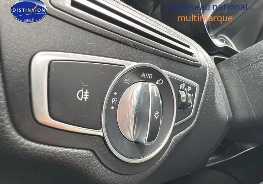 Gros plan sur le sélecteur de phares d'une Mercedes Classe C 180 d business gris alu, intérieur noir texturé.