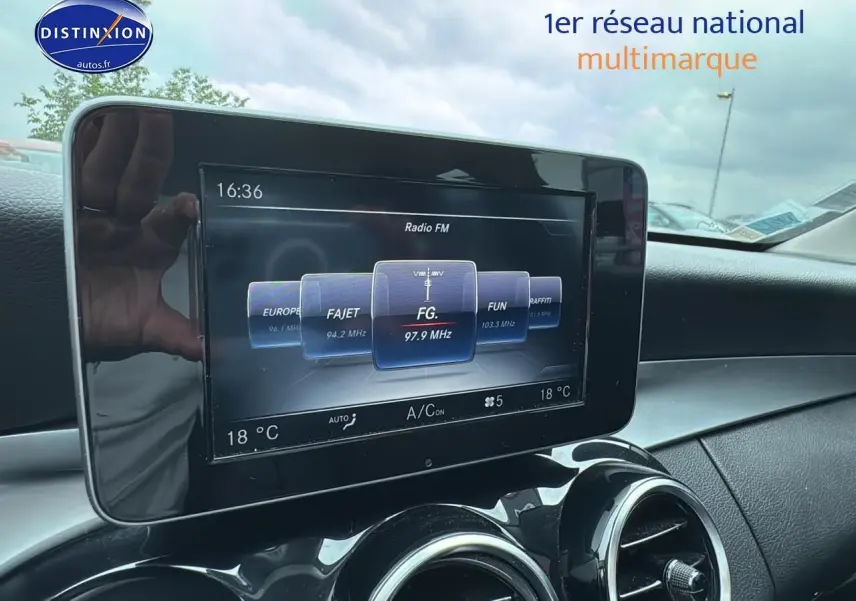 Écran multimédia central affichant la radio FM dans l'habitacle d'une Mercedes Classe C gris alu de 2017.