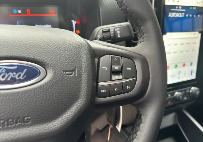 Gros plan sur le volant cuir multifonctions du Ford Ranger 2026 avec commandes intégrées et écran tactile en arrière-plan.