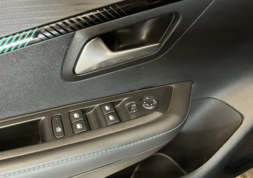 Détail de la porte côté conducteur de la Peugeot 208 bleu Vertigo, avec commandes des vitres et rétroviseurs électriques.