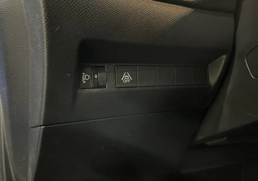 Gros plan sur les commandes de réglage des phares et de désactivation de l’aide au maintien de voie dans une Peugeot 208 1.5 BlueHDi 2020.