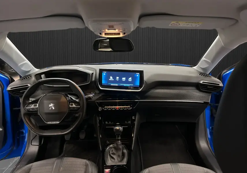 Vue intérieure avant de la Peugeot 208 Bleu Vertigo, montrant le tableau de bord avec écran tactile et volant compact multifonction.
