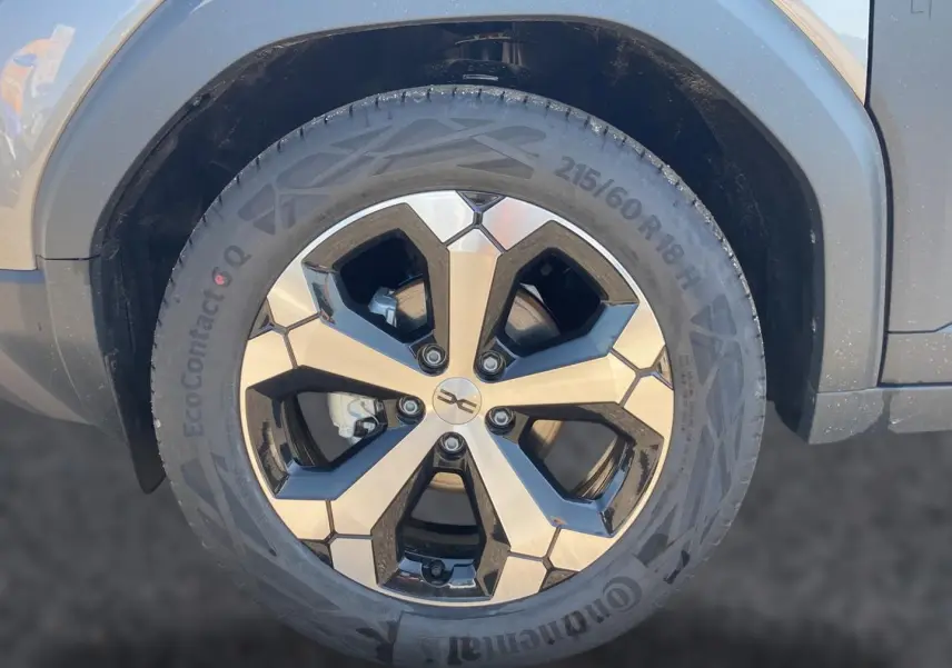 Gros plan sur la roue avant droite du Dacia Duster gris schiste, mettant en valeur la jante alu au design géométrique.