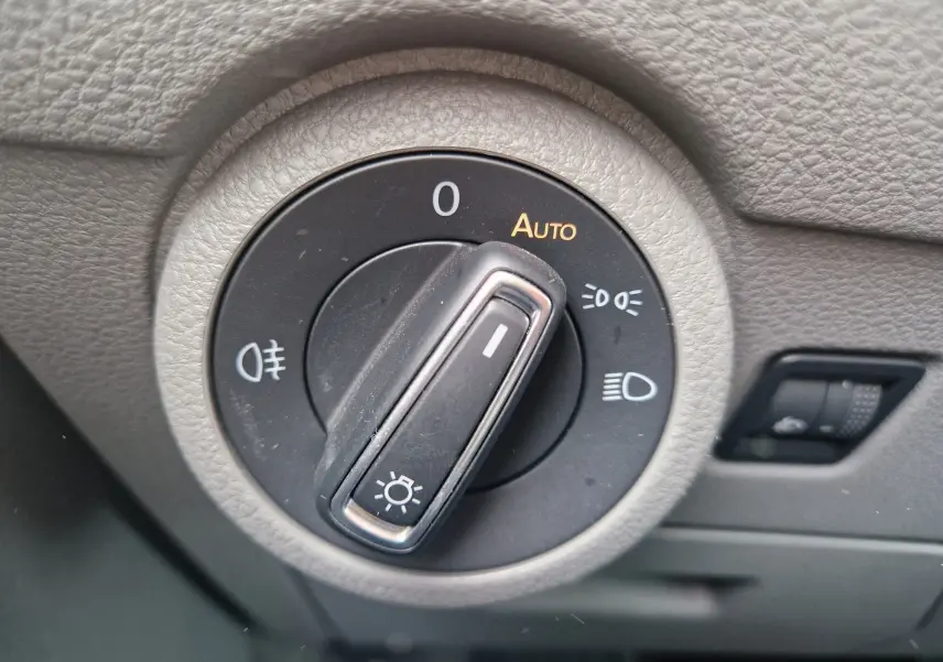 Gros plan sur le sélecteur de phares du Volkswagen California 2021, avec molette en position automatique sur tableau de bord gris.