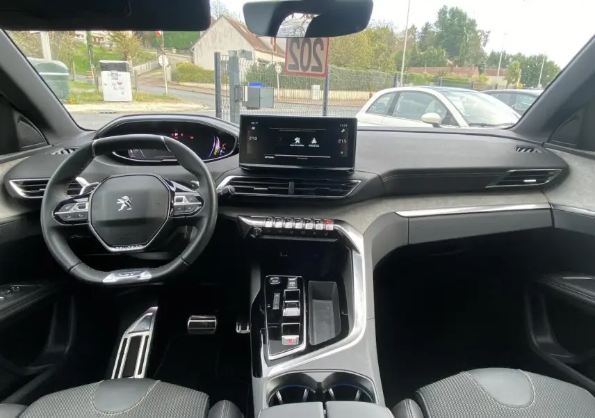 Intérieur du Peugeot 3008 2023 hybride, vue avant du poste de conduite avec écran tactile et volant compact.