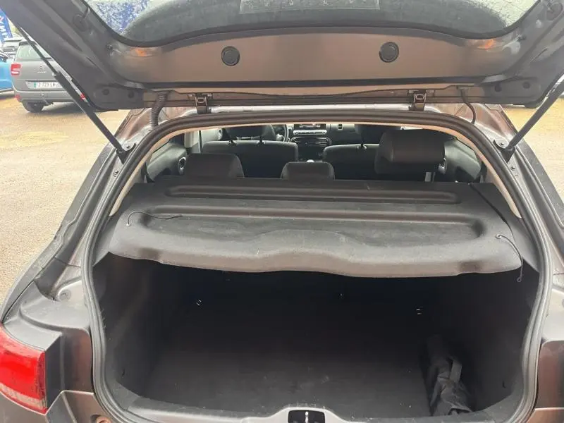 Coffre ouvert vu de l'arrière d'une Citroën C4 Cactus gris Platinium avec cache-bagages en place.