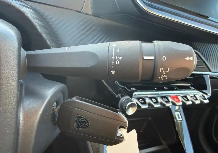 Gros plan sur la commande d’essuie-glace et la clé insérée dans le contact d’une Peugeot 208 jaune 2025.