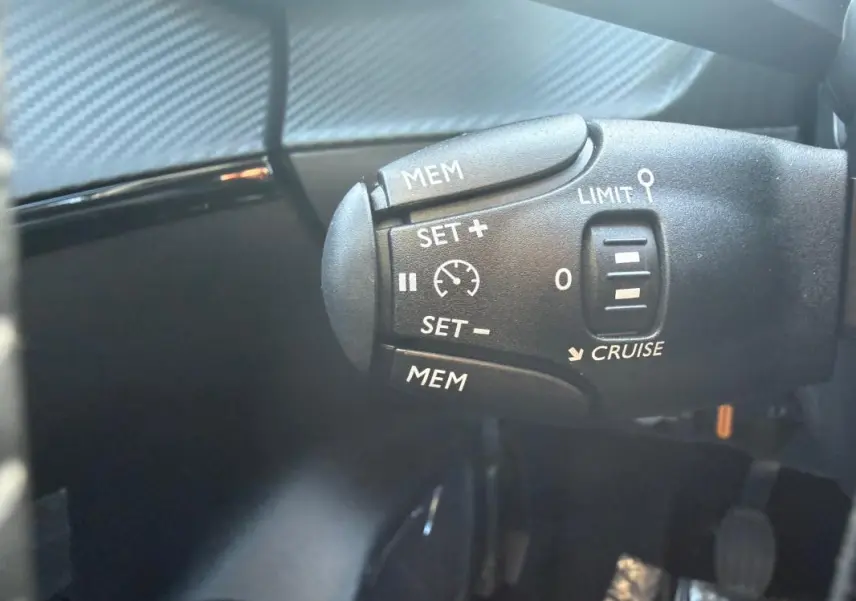 Gros plan sur la commande de régulateur de vitesse dans l'habitacle d'une Peugeot 208 jaune 2025.