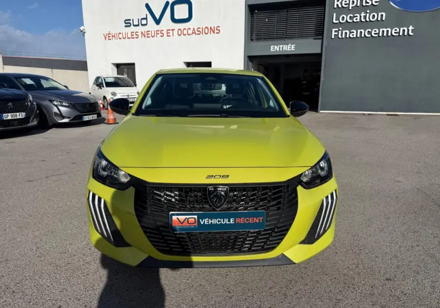 Vue de face d'une Peugeot 208 jaune vif 2025 avec calandre noire et feux diurnes à LED en griffes.