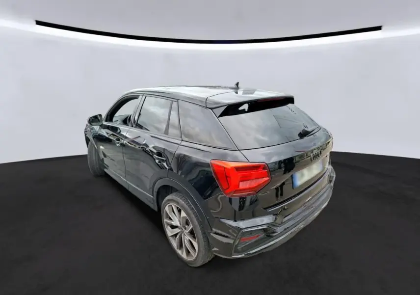 Audi Q2 noir vue 3/4 arrière droit, jantes alu et feux arrière LED dans un studio blanc.