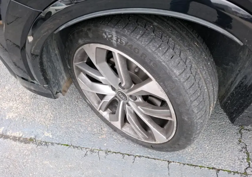 Gros plan sur la roue avant gauche noire d’un Audi Q2 2023 avec jante alu à 5 doubles branches.