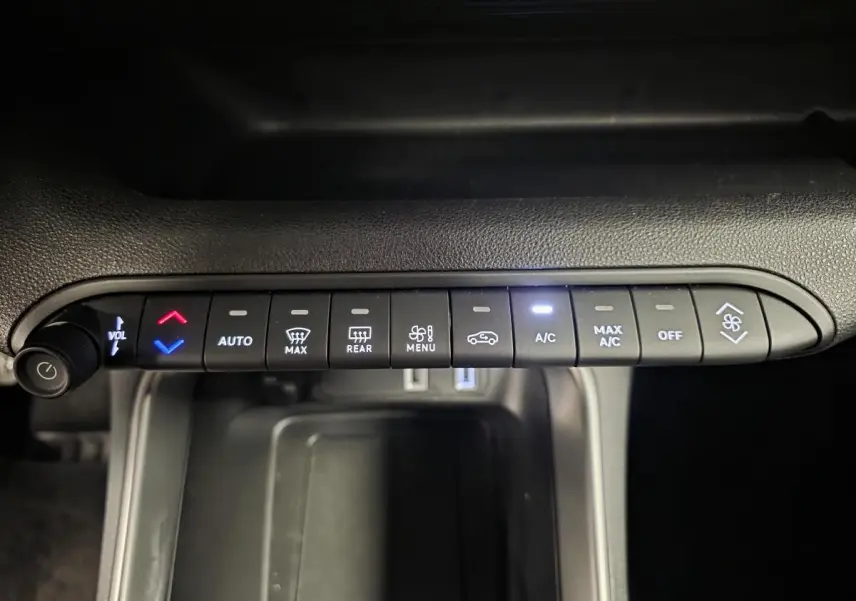 Vue rapprochée des commandes de climatisation et volume du Jeep Avenger 2025, boutons noirs avec éclairage blanc et rouge.