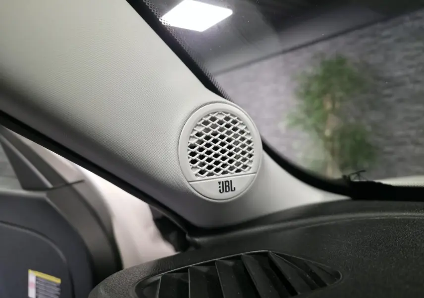 Gros plan sur l'enceinte JBL blanche intégrée à l'angle avant gauche du tableau de bord du Jeep Avenger blanc.