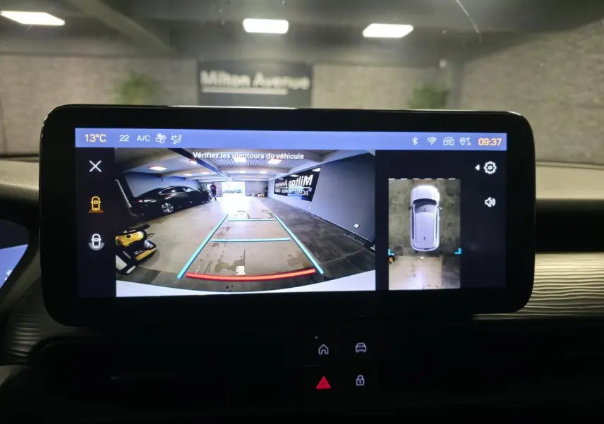Écran tactile intérieur montrant la caméra de recul et vue 360° du Jeep Avenger blanc, tableau de bord en arrière-plan.