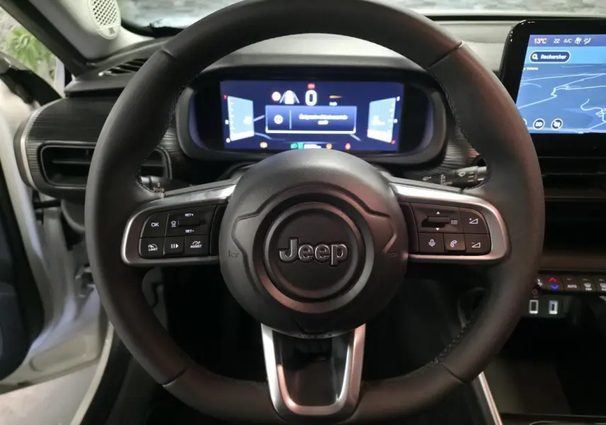 Vue intérieure centrée sur le volant noir du Jeep Avenger 2025 avec tableau de bord numérique et écran tactile.