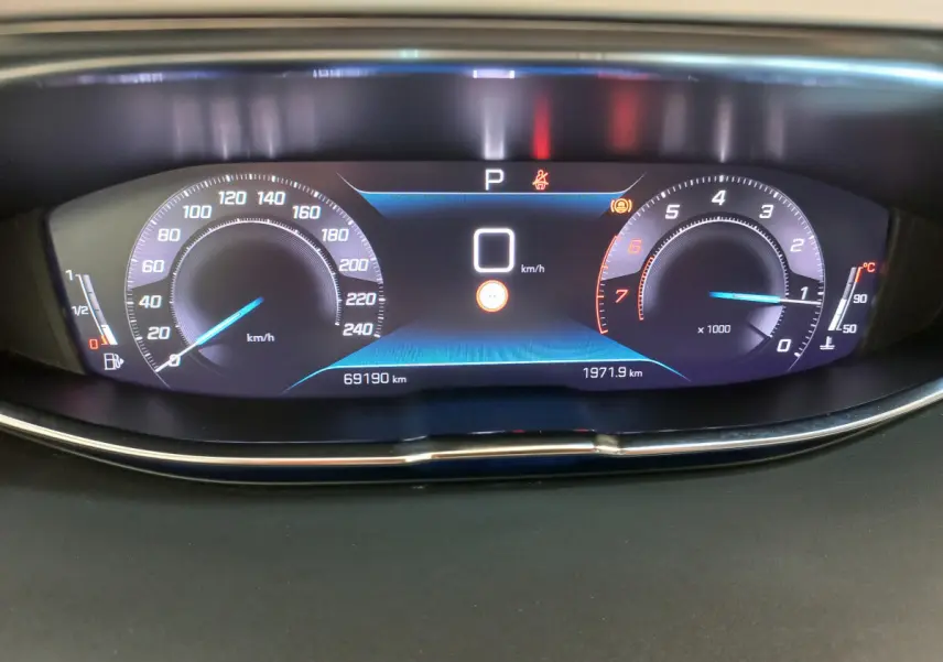 Affichage numérique du tableau de bord du Peugeot 5008 2021, vitesse à 0 km/h, compte-tours et jauge essence visibles.