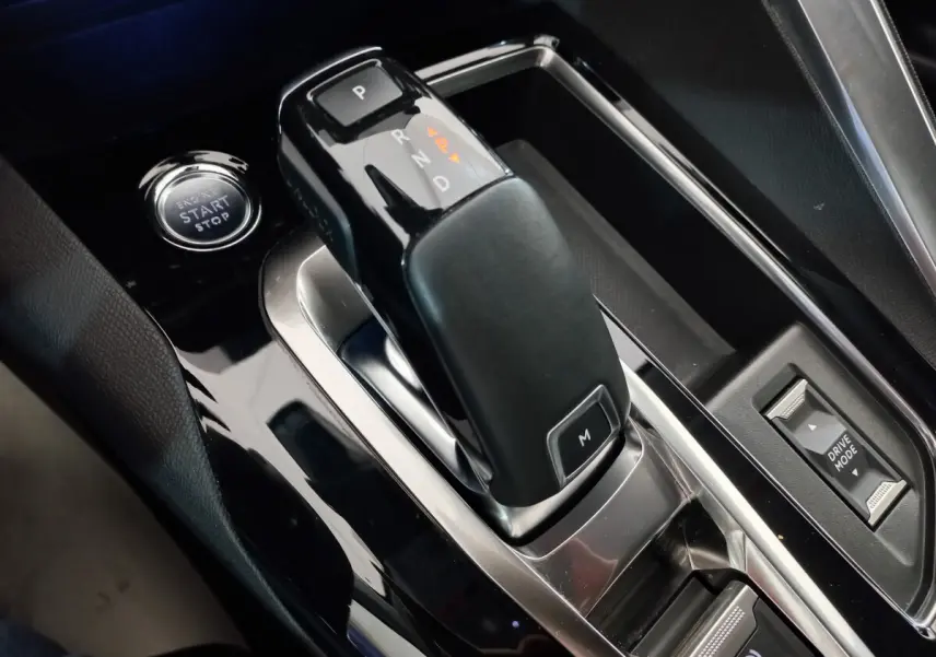 Gros plan sur la console centrale noire brillante du Peugeot 5008 2021, avec levier de vitesse automatique et bouton start/stop.