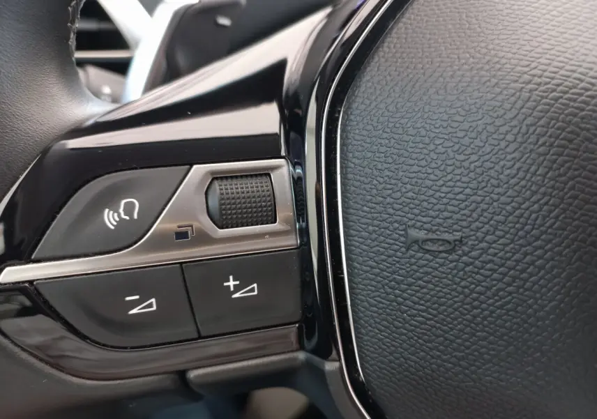 Gros plan sur les commandes vocales et volume du volant cuir noir du Peugeot 5008 gris foncé 2021.