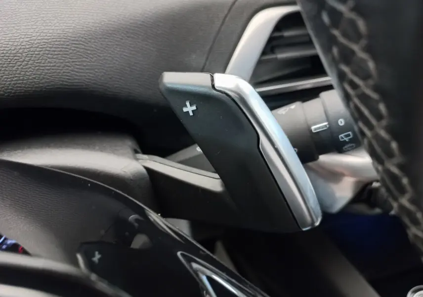 Gros plan sur la palette de changement de vitesse + côté droit du volant cuir noir du Peugeot 5008 gris foncé.