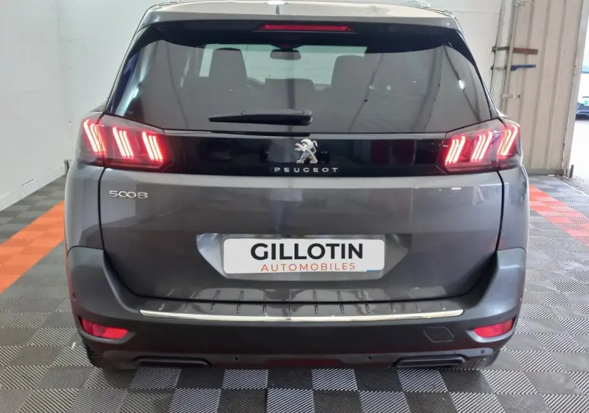 Vue arrière d'un Peugeot 5008 gris foncé avec feux LED caractéristiques et logo lion au centre du hayon.