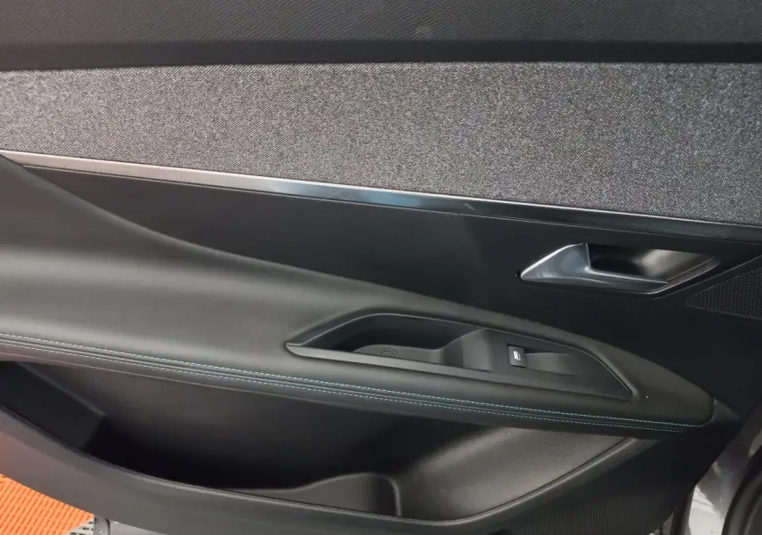 Gros plan sur la garniture de la porte côté gauche du Peugeot 5008 gris foncé, avec couture bleue visible.