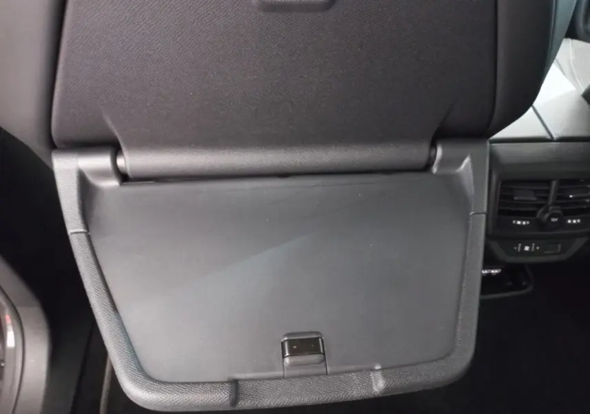 Gros plan sur la tablette rabattable noire du siège avant droit du Peugeot 5008 gris foncé, avec aérateurs arrière visibles.