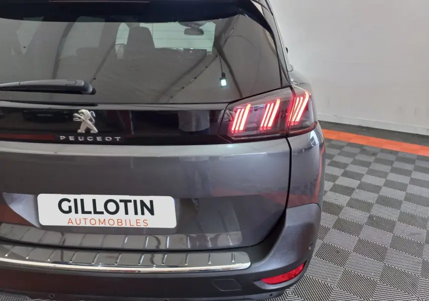 Vue arrière droite du Peugeot 5008 gris foncé avec feux LED distinctifs et logo Peugeot visible.