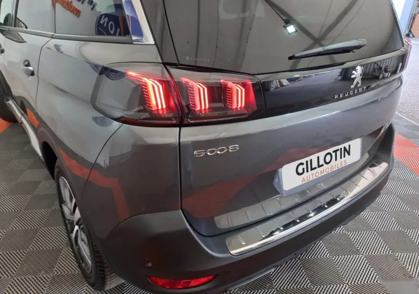 Vue 3/4 arrière droite du Peugeot 5008 gris foncé avec feux arrière LED et logo visible sur hayon.