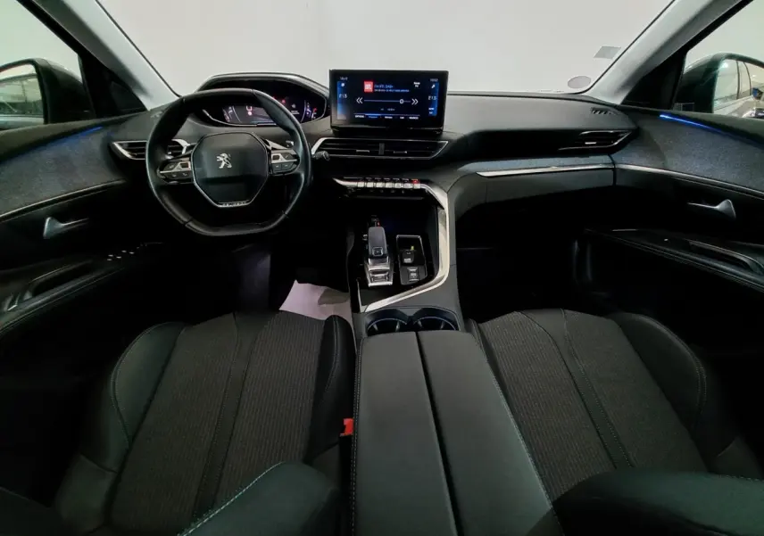 Intérieur Peugeot 5008 2021 vu de face, tableau de bord moderne avec écran tactile et volant cuir noir.