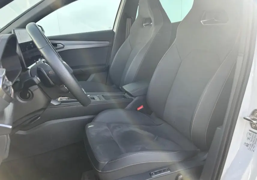 Vue intérieure côté conducteur du CUPRA Formentor blanc neige, sièges sport noirs avec surpiqûres contrastées et volant cuir.