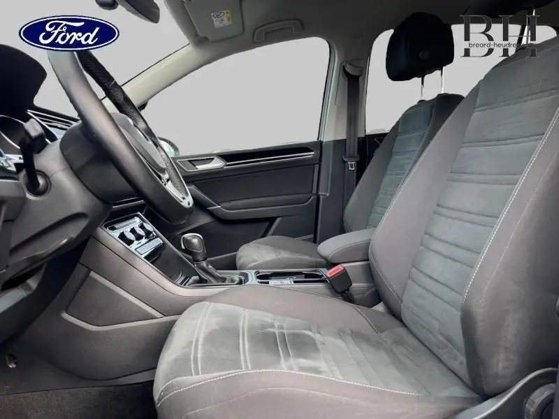 Vue intérieure côté conducteur du Volkswagen Touran 2021, sièges cuir Vienna noir titane et console centrale visible.