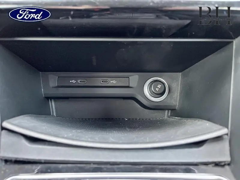 Gros plan sur la prise 12V et ports USB-C dans le rangement avant d'un Volkswagen Touran argent métallisé.