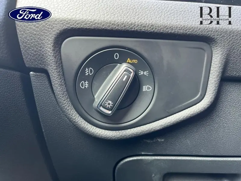 Commande des phares en gros plan sur tableau de bord noir, avec réglage automatique activé.