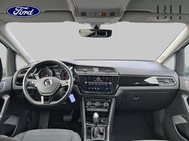 Vue intérieure avant du Volkswagen Touran 1.5 TSI Carat 2021 avec tableau de bord noir et volant cuir multifonction.