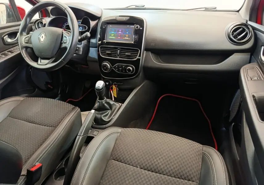 Intérieur de Renault Clio Intens 2018, vue avant centrée sur tableau de bord et boîte manuelle, sièges noirs.