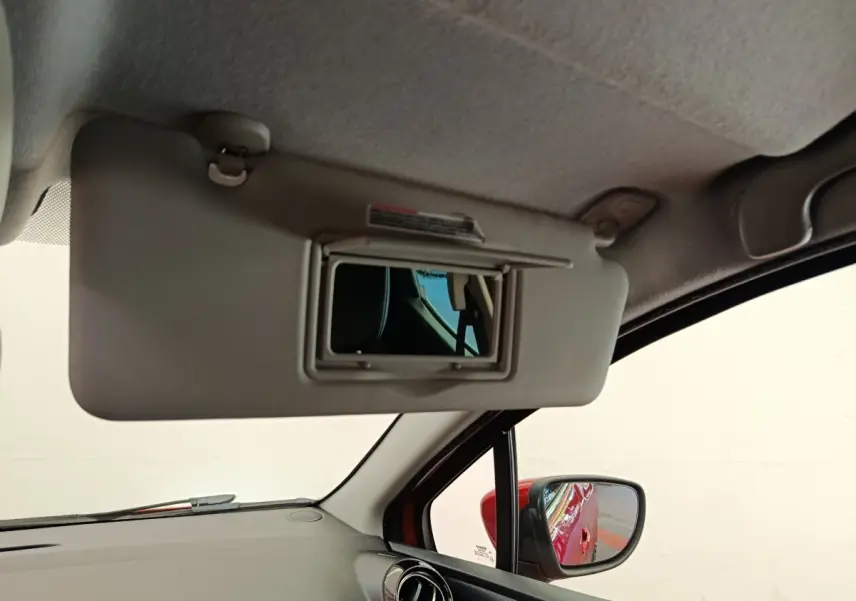 Intérieur de la Renault Clio Intens rouge, vue côté passager avec pare-soleil et rétroviseur extérieur visible.