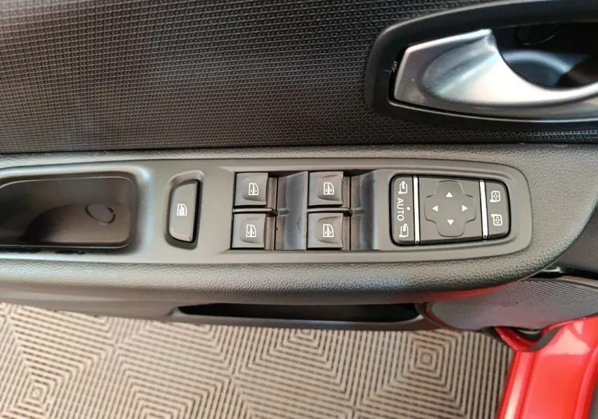 Vue rapprochée de la commande des vitres et rétroviseurs sur la porte côté conducteur d’une Renault Clio rouge 2018.